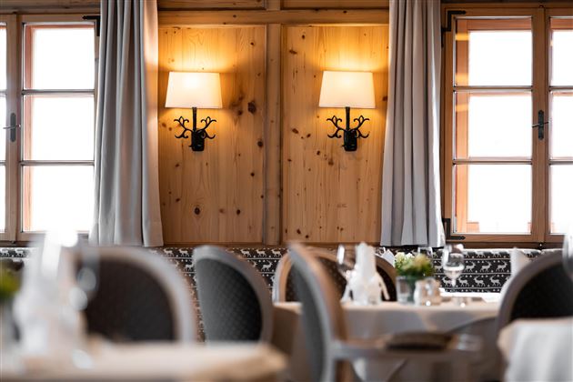 Ein gemütliches Restaurant mit Holzvertäfelungen und stilvollen Lampen. Die Fenster lassen viel Licht herein und schaffen eine einladende Atmosphäre.