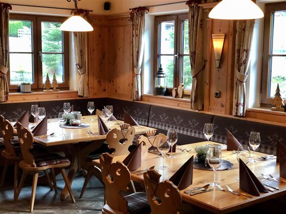 Ein gemütlicher Speisesaal mit holzgetäfelten Wänden und schön gedeckten Tischen. Die Umgebung ist warm und einladend, ideal für ein gutes Essen.