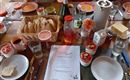 A set table with various foods and drinks. At the center are fresh rolls, desserts, and a menu card.