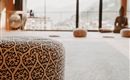 A cozy yoga room with a decorative cushion and a view of the mountains. Large windows let in plenty of light and create a relaxing atmosphere.