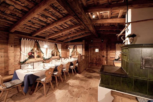 A cozy restaurant with wooden walls and a large table. The room is warm and inviting, ideal for a rustic dining experience.