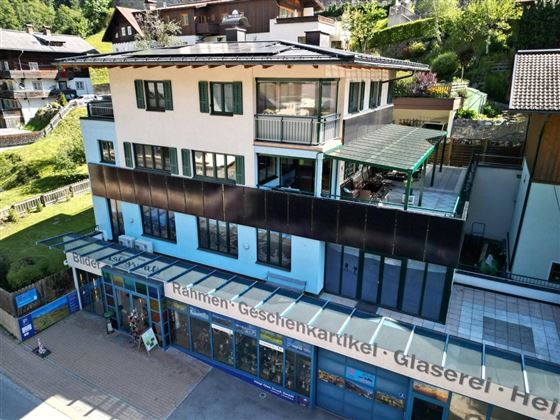 A multi-story building in a picturesque setting. On the ground floor, there is a shop for frames and gifts.