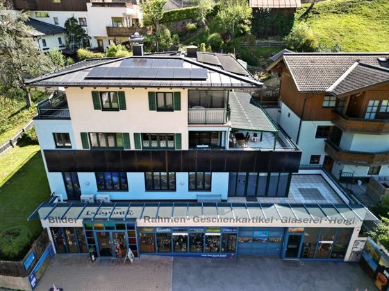 A modern building with a store for picture frames and greeting cards. The house has green window shutters and a modern roof structure.