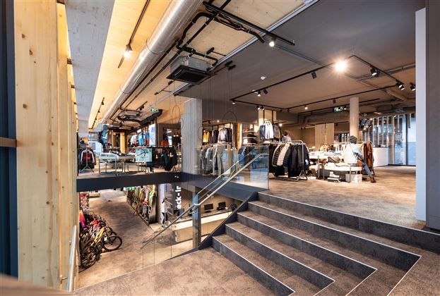 Ein moderner Bekleidungsgeschäft mit mehreren Ebenen. Die Einrichtung ist hell und einladend, mit Regalen gefüllt mit Kleidung und Accessoires.