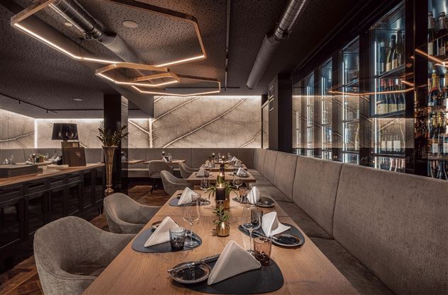 Ein modernes Restaurant mit eleganter Einrichtung und warmem Licht. Die Tische sind stilvoll gedeckt und laden zum Verweilen ein.