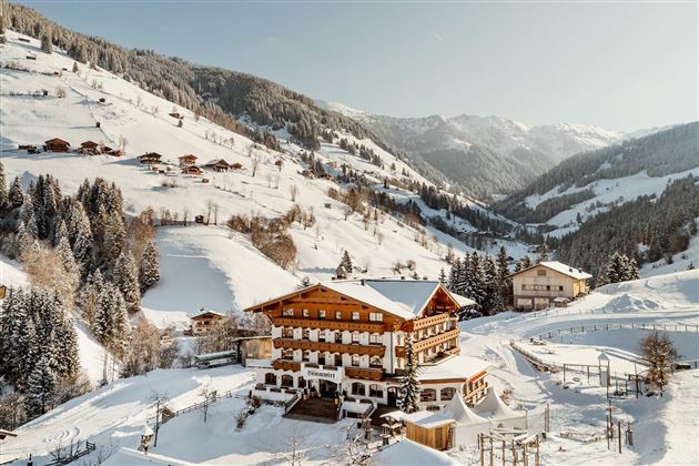 A picturesque mountain village in winter with snow-covered hills. Wooden buildings and trees create a cozy atmosphere.