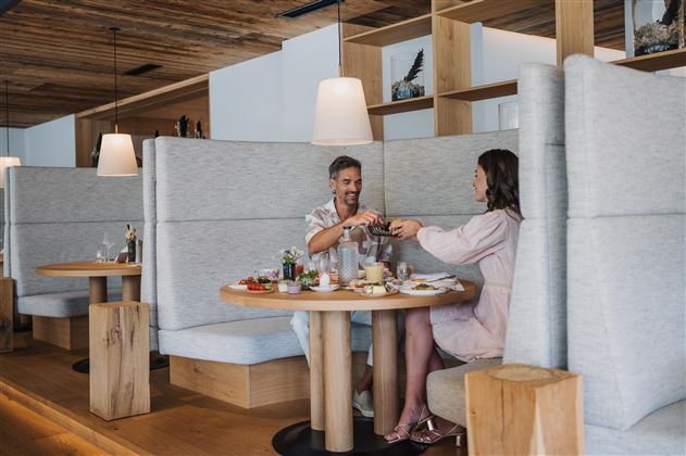 A couple is sitting at a table in a modern restaurant. They are enjoying a meal together and have drinks in front of them.