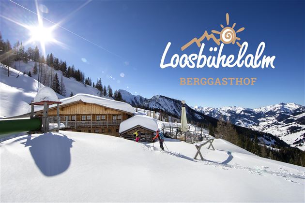 Ein malerischer Berghof im Schnee mit Sonnenstrahlen und umliegenden Bergen. Der Ort strahlt eine gemütliche Atmosphäre aus, ideal für einen winterlichen Aufenthalt.