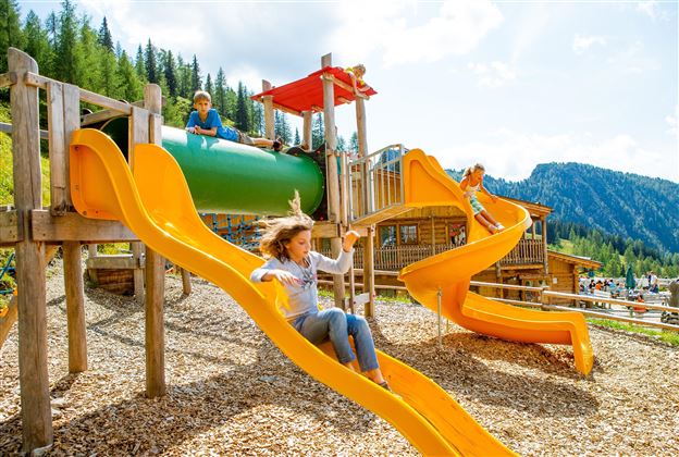 A playground with colorful slides and a tube. Children play and have fun in a beautiful landscape.