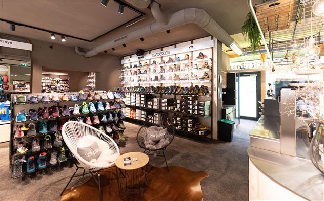 Ein modernes Schuhgeschäft mit einer großen Auswahl an Schuhen in unterschiedlichen Farben und Stilen. Bequeme Sitzmöglichkeiten laden zum Verweilen ein.