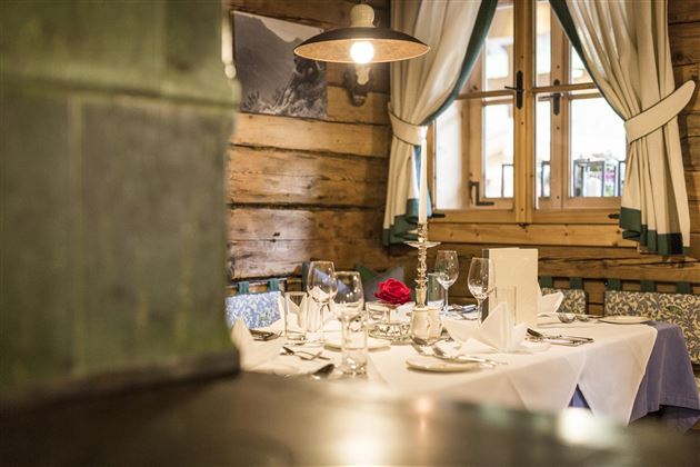 A cozy restaurant with an elegantly set table. The wooden paneling and the windows create a warm atmosphere.