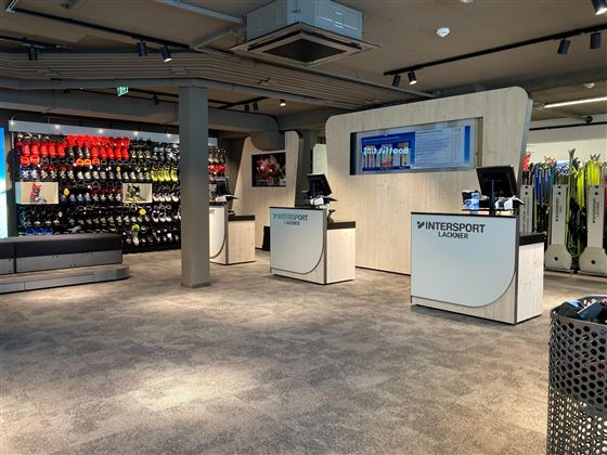 Ein moderner Sportladen mit mehreren Kassen. Im Hintergrund sind Skiausrüstungen und -zubehör aufgereiht.