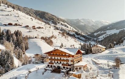 Ein malerisches Bergdorf im Winter mit schneebedeckten Hügeln. Holzgebäude und Bäume schaffen eine gemütliche Atmosphäre.