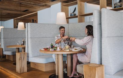 Ein Paar sitzt an einem Tisch in einem modernen Restaurant. Sie genießen ein gemeinsames Essen und haben Getränke vor sich.