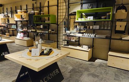 Ein modernes Geschäft mit Regalen und Tischen aus Holz. Es gibt eine Vielzahl von Produkten, die ordentlich präsentiert werden.