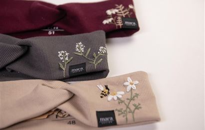 Drei stylische Haarschmuckstücke in verschiedenen Farben liegen übereinander. Jedes hat florale Stickereien und bringt einen frischen, eleganten Look.