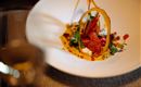 Ein kunstvoll angerichteter Teller mit einer kreativen Speise. Frische Zutaten und dekorative Elemente heben das Gericht hervor.