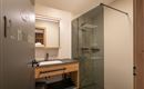 A modern bathroom with a glass shower and a wooden sink. There is also a large mirror and a bright, friendly atmosphere.