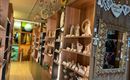 A cozy shop with shelves full of handcrafted figures and decorations. A large mirror hangs on the wall and the space has a friendly atmosphere.