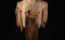 A sculptural representation of a human torso made of wood. The head is richly detailed, while the lower part ends in irregular wooden fragments.