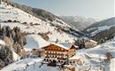 A picturesque mountain village in winter with snow-covered hills. Wooden buildings and trees create a cozy atmosphere.