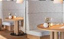 A modern restaurant with cozy benches and wooden tables. The subtle lighting creates an inviting atmosphere.