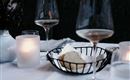 An elegantly set table with wine glasses and a bowl of bread. Soft candlelight creates a cozy atmosphere.