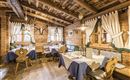 A cozy restaurant with rustic wooden interior and traditional decoration. The tables are beautifully set and the windows let in a lot of light.