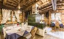 A cozy restaurant with wooden-paneled walls and traditional furniture. Elegant tablecloths and an elegant table decoration can be seen on the tables.