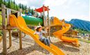A playground with colorful slides and a tube. Children play and have fun in a beautiful landscape.