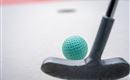A putter stands next to a green golf ball on a white background. The scene suggests a game of golf or mini-golf.