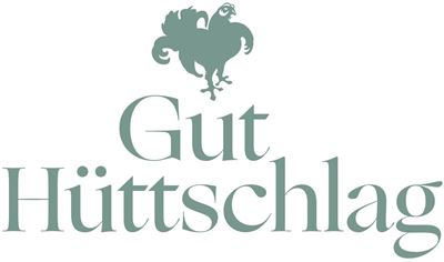 An elegant logo of "Gut Hütschtlag". It features a rooster above the inscription in soft colors.