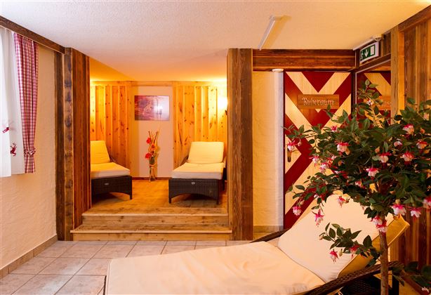 A cozy wellness area with wooden paneling and loungers. Soft lighting creates a relaxed atmosphere.