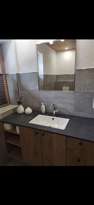A modern bathroom with an elegant sink and a large mirror. The walls are painted in neutral colors and there are decorative elements on the sink.