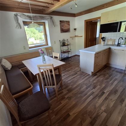 A bright and welcoming kitchen with a dining table and chairs. The room has modern furniture and large windows that let in plenty of light.