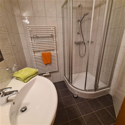 A modern bathroom with a shower and a sink. Towels in various colors are ready.