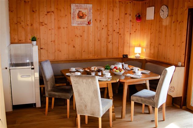 An inviting dining area with wooden decor and a table set for a festive meal. Fresh fruit and dishes are ready for a meal.