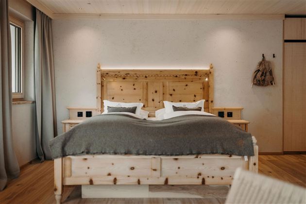 A modern bedroom with a wood bed and a cozy blanket. Soft colors and warm wood details create an inviting atmosphere.