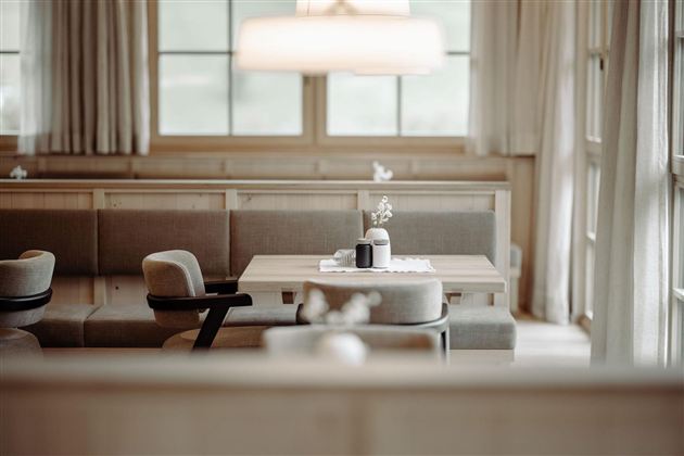 A modern dining room with wooden-colored walls and cozy furniture. The table is simply decorated and the light is soft.
