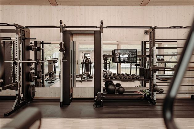 A modern gym with various machines and mirrors. The room is bright and well-equipped for an effective workout.