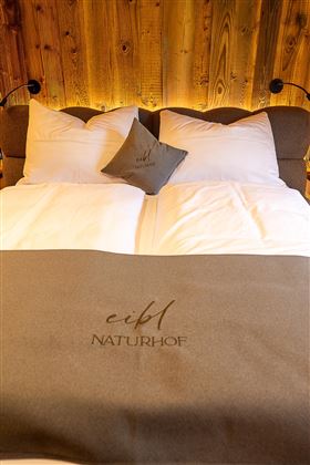 Ein gemütliches Schlafzimmer mit einem bequemen Bett und weichen Kissen. Die warme Holzverkleidung schafft eine einladende Atmosphäre.