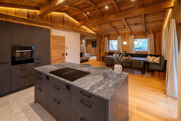 Moderne Küche mit einer großen Kochinsel aus Granit. Holzwände und -decken sorgen für eine gemütliche Atmosphäre.