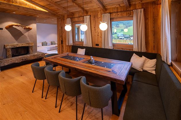 Ein gemütlicher Essbereich mit einem großen Holztisch und modernen Stühlen. Große Fenster bieten einen Blick auf die Landschaft und sorgen für helle Beleuchtung.