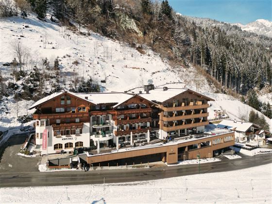 A charming hotel in the mountains, surrounded by snowy landscapes. The architecture combines wood and modern elements.