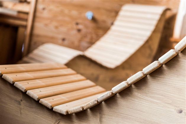 A detailed close-up of wooden loungers in a relaxing space. The ergonomic shapes convey a cozy atmosphere.