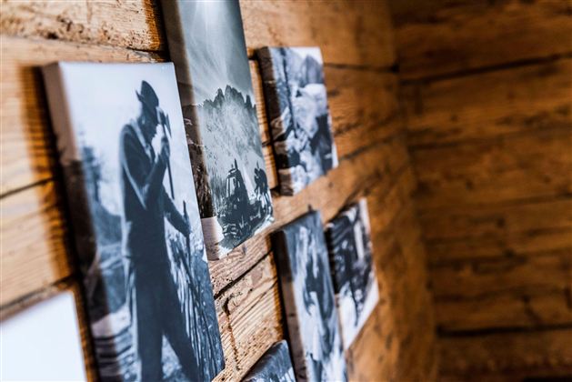 Walls with black-and-white photographs in a rustic wooden setting. The images depict various scenes and people.