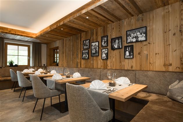 Ein gemütliches Restaurant mit Holzwänden und stilvollen Tischen. Die Wände sind mit Bildern geschmückt, und das Licht schafft eine einladende Atmosphäre.