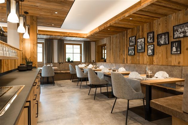 Ein modernes Restaurant mit Holzverkleidung und eleganten Tischen. Die Atmosphäre ist einladend und gemütlich, mit sanfter Beleuchtung und dekorativen Bildern an den Wänden.