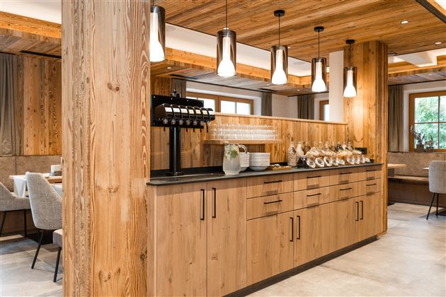 Ein modernes Restaurant mit Holzdetails und eleganten Lampen. Die Theke ist mit Gläsern und Geschirr dekoriert.
