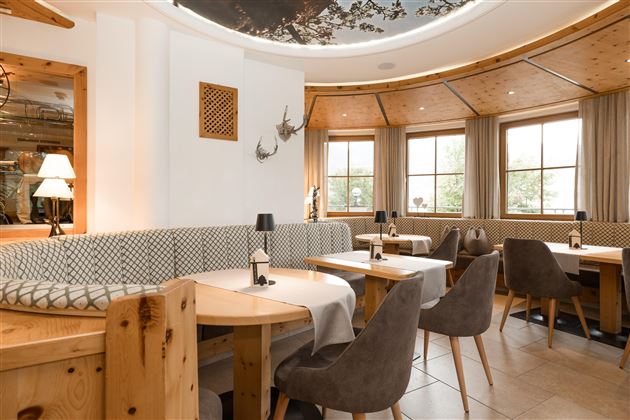 Ein einladendes Restaurant mit holzvertäfelten Wänden und gemütlichen Sitzbereichen. Große Fenster lassen viel Tageslicht herein und schaffen eine angenehme Atmosphäre.